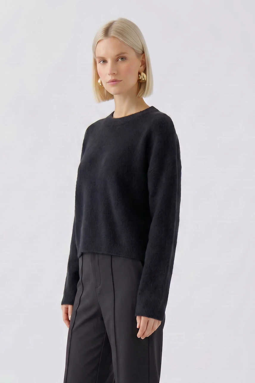 Schlichter Damen-Pullover: Frau im schwarzen Pullover mit langen Ärmeln und geradem Schnitt, dezenter Look.