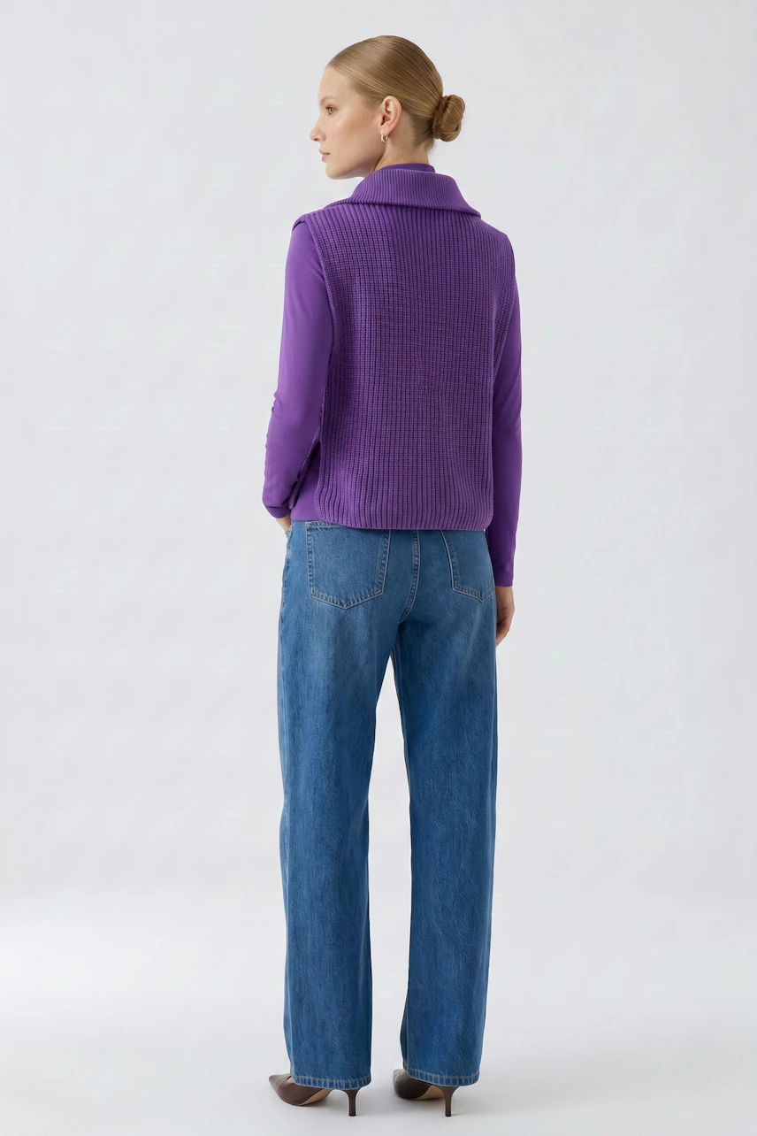 Woman in purple pullunder and blue jeans, viewed from the back, showcasing casual style.