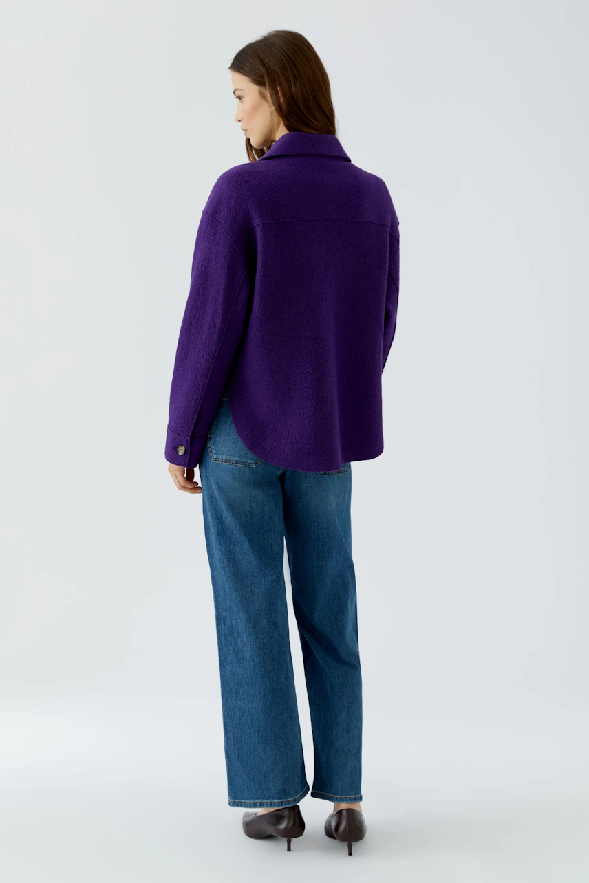 Casual women's overshirt: Woman in a purple overshirt and blue jeans, viewed from the back.
