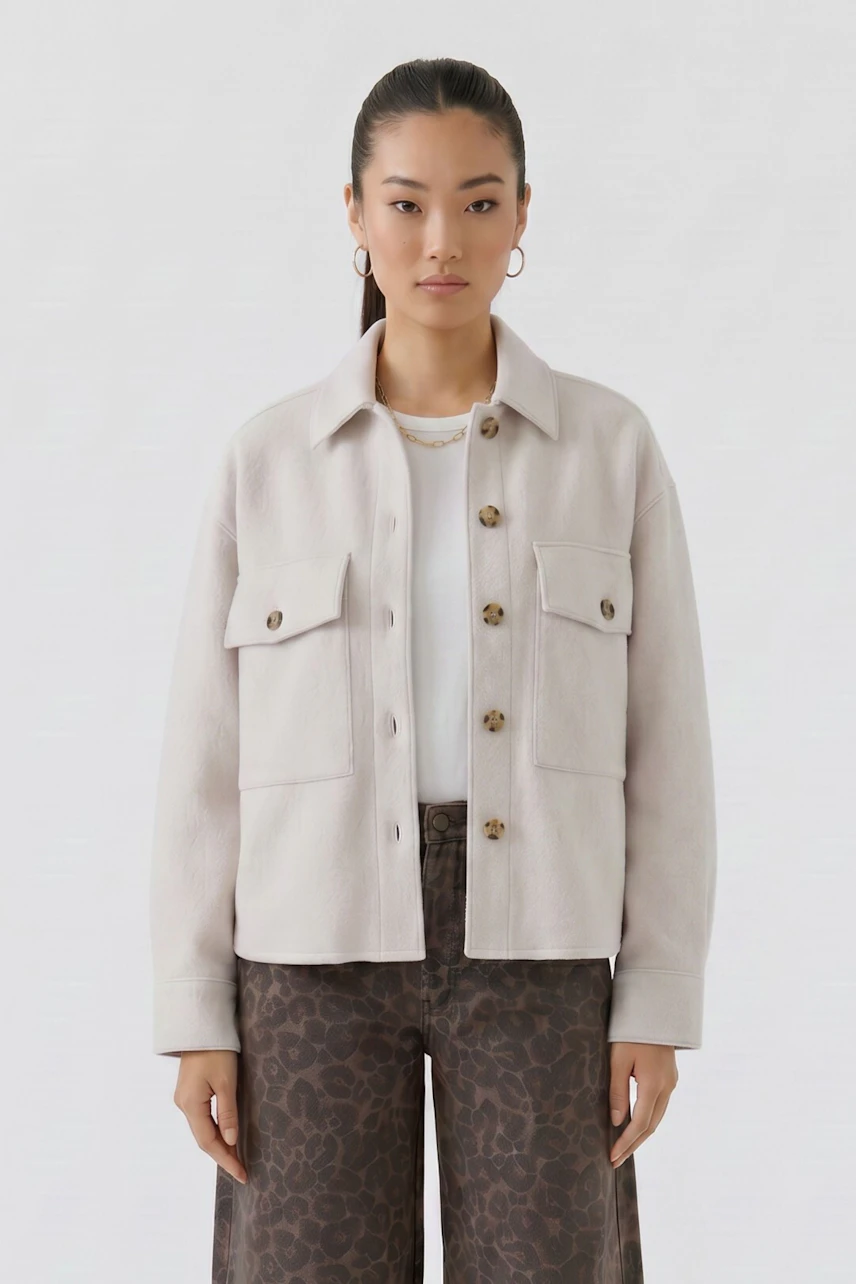 Woman in beige overshirt with button closure and chest pockets, paired with leopard print pants.