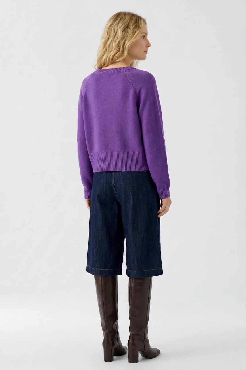 Woman in purple pullover, dark denim culottes, and tall brown boots, viewed from the back.