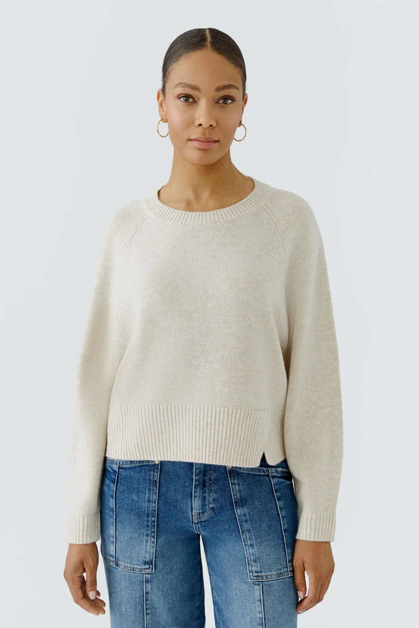 Lässiger Damen-Pullover: Frau im cremefarbenen Pullover und blauen Jeans, schlicht und modern.