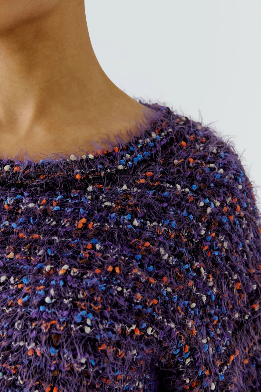 Frau im flauschigen, bunten Pullover aus grobem Strick, Nahaufnahme des Oberteils.