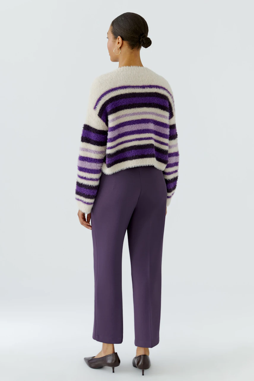 Woman in striped pullover: Back view of a woman wearing a fluffy striped pullover in purple and white.