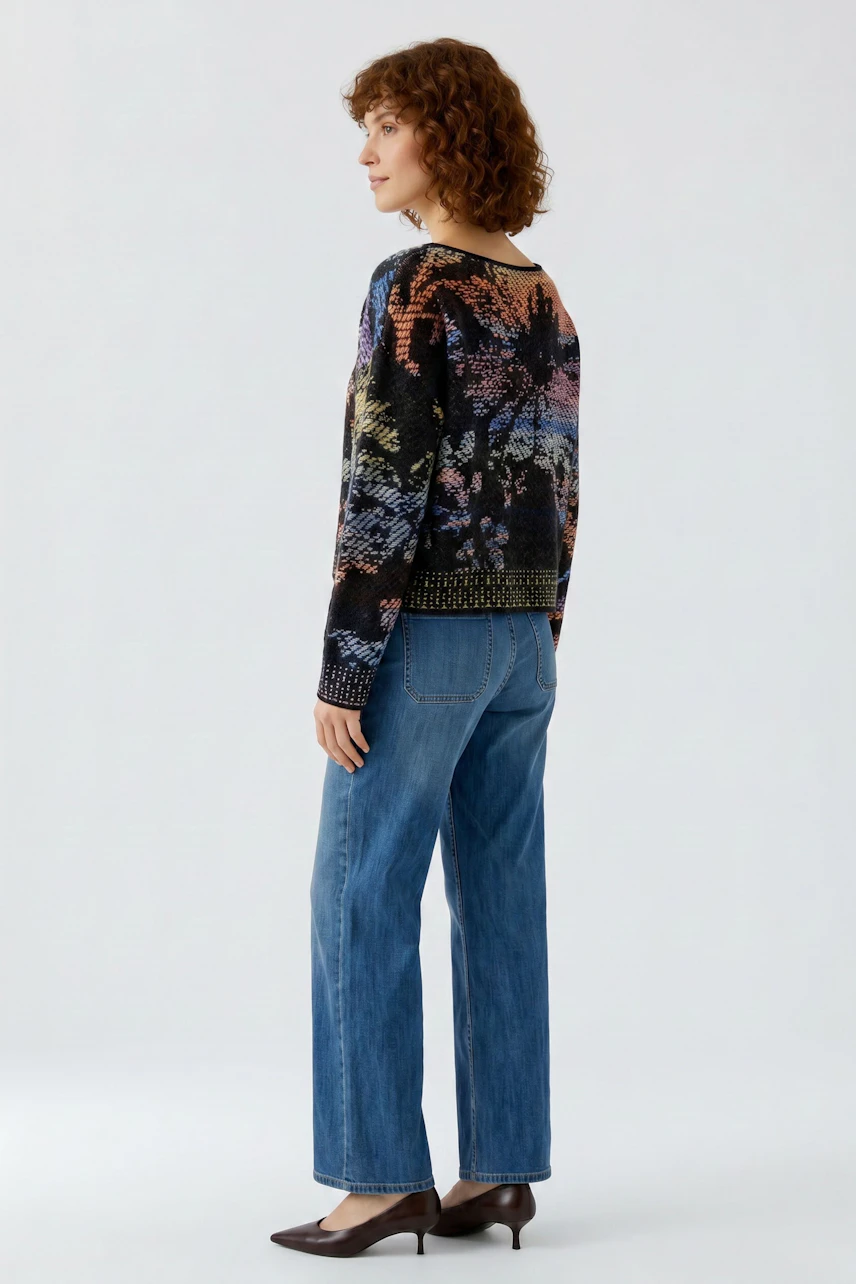 Casual women's pullover: Woman in a colorful patterned pullover and blue jeans, standing confidently.