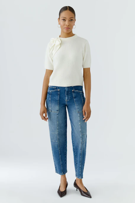 White pullover with short sleeves and a large bow on the shoulder.