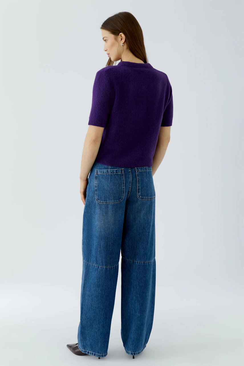 Casual women's pullover: Woman in a purple pullover and wide-leg jeans, viewed from the back.