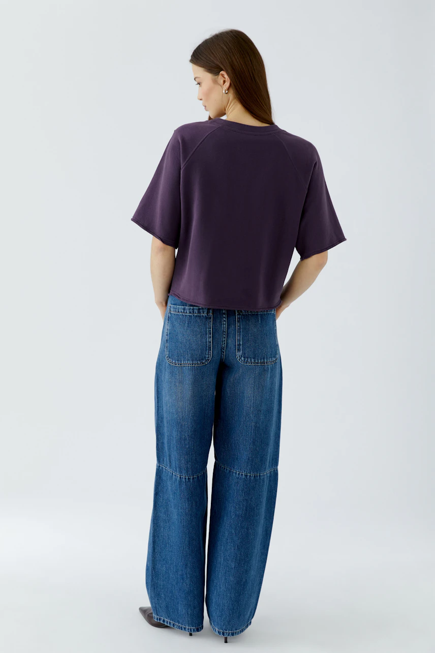 Lässiges Damen-Sweatshirt: Frau im lila Sweatshirt und blauer Jeans, von hinten gesehen.