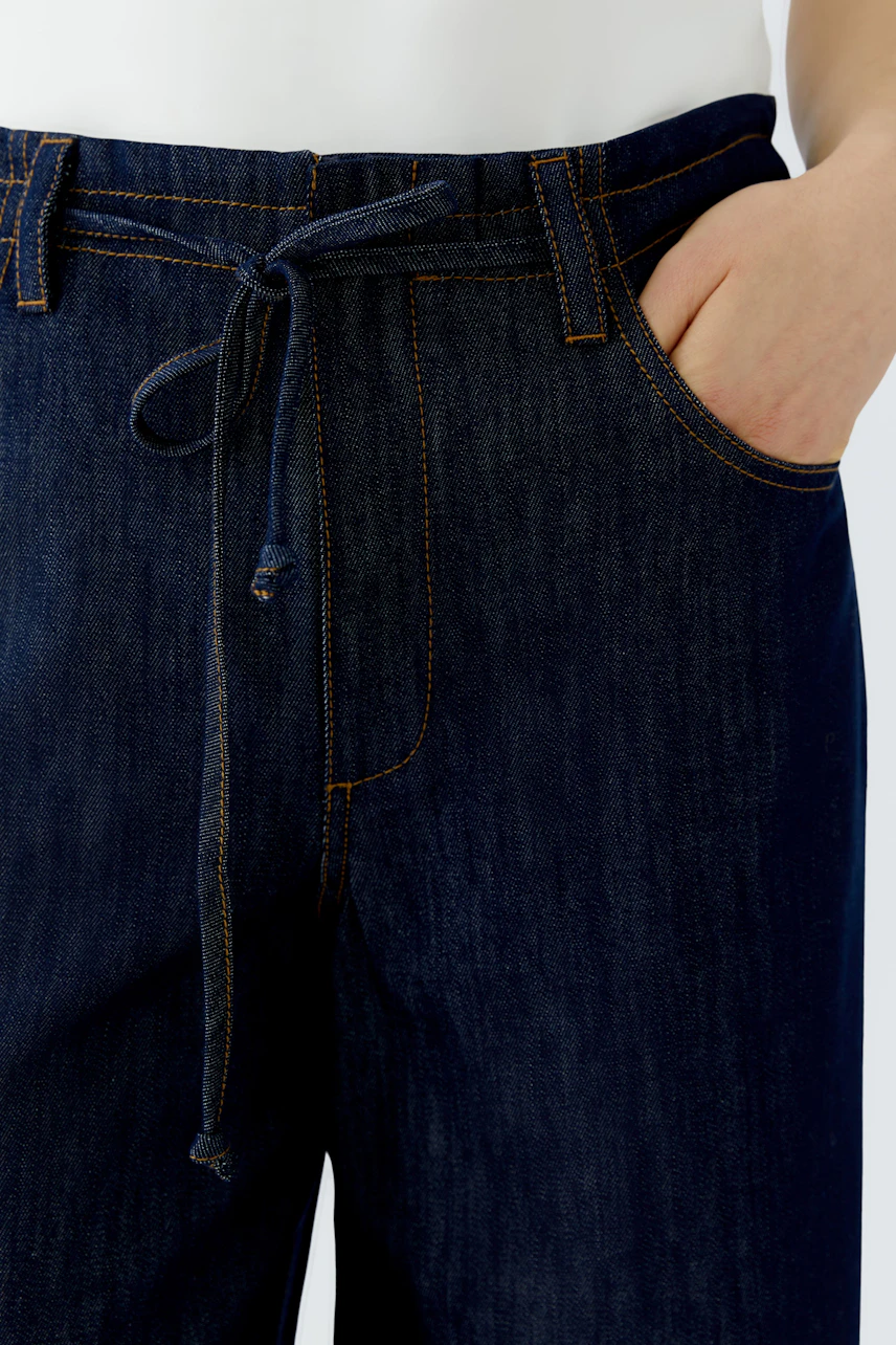 Jeans Wide Leg: Dunkelblaue Jeans mit weitem Bein und Bindegürtel, lässig und modern.