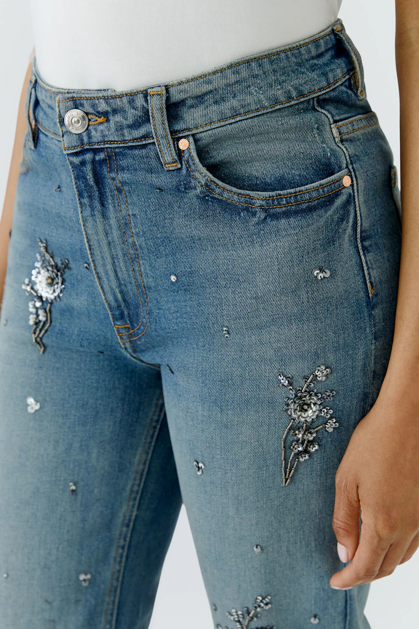 Relaxed jeans with floral embroidery worn by a woman, showcasing casual style and comfort.