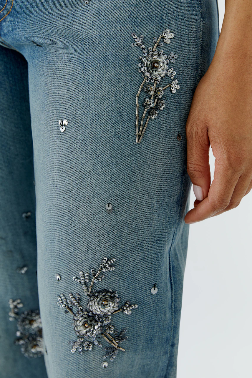 Relaxed jeans with floral embroidery, worn by a woman. Casual and stylish for everyday wear.