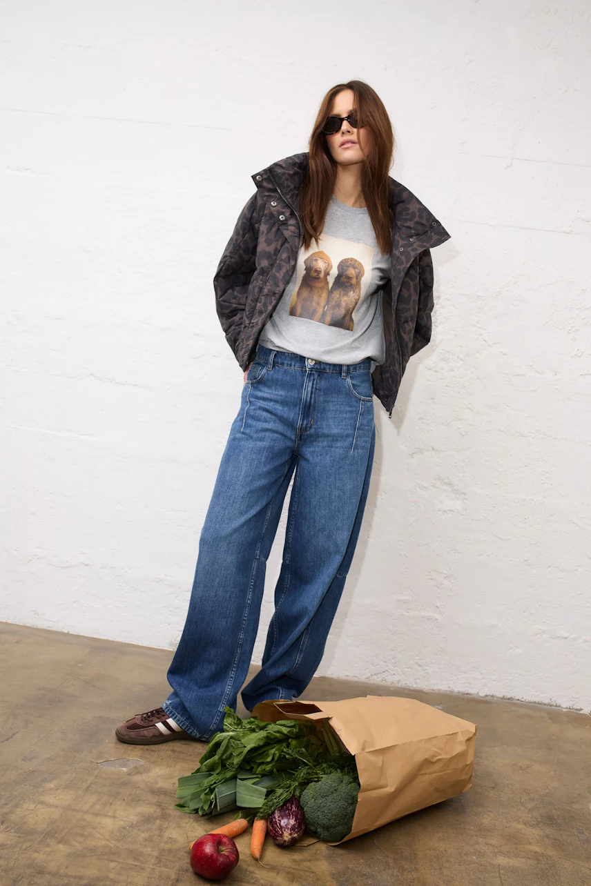 Woman in floral pullover and relaxed Jeans Barrel, sitting casually with an orange sweater tied at waist.