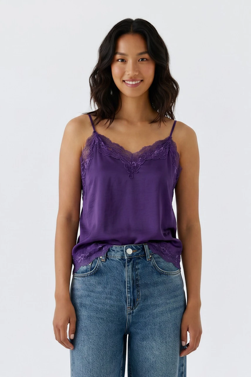 Lässiges Damen-Top: Frau im lila Spitzentop und Jeans, lächelt entspannt.