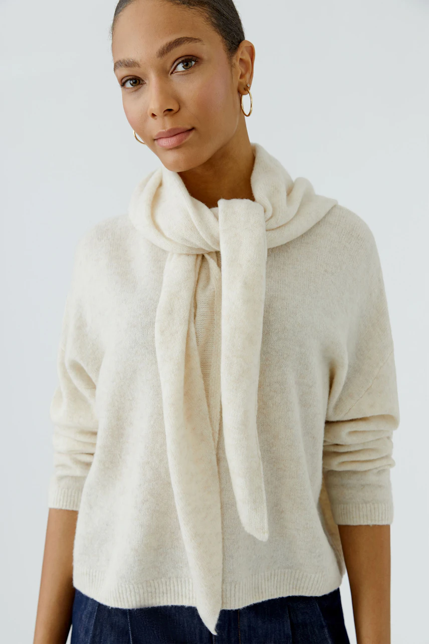 Woman in cozy scarf and pullover, soft texture, casual style.