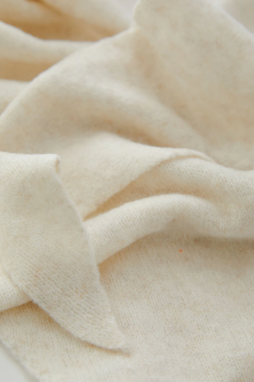 Soft beige scarf in cozy fabric, perfect for layering. No model, just the scarf's texture and color.