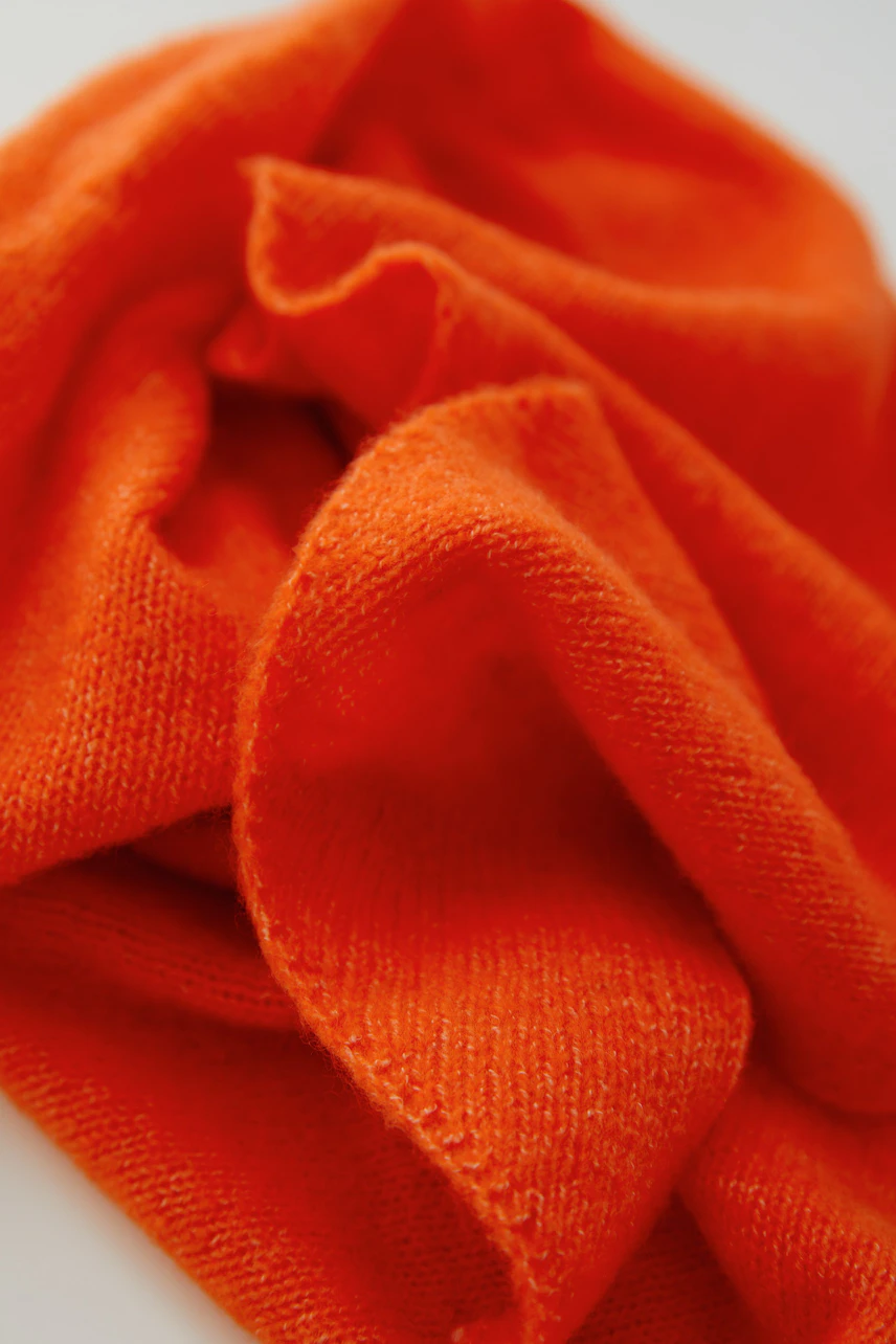 Bright orange scarf in soft fabric, perfect for adding a pop of color to any outfit.
