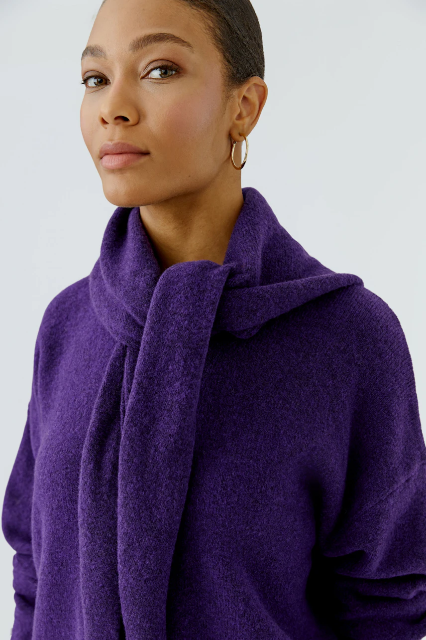 Woman in a purple scarf, looking confident. The scarf is wrapped around her neck, adding warmth.