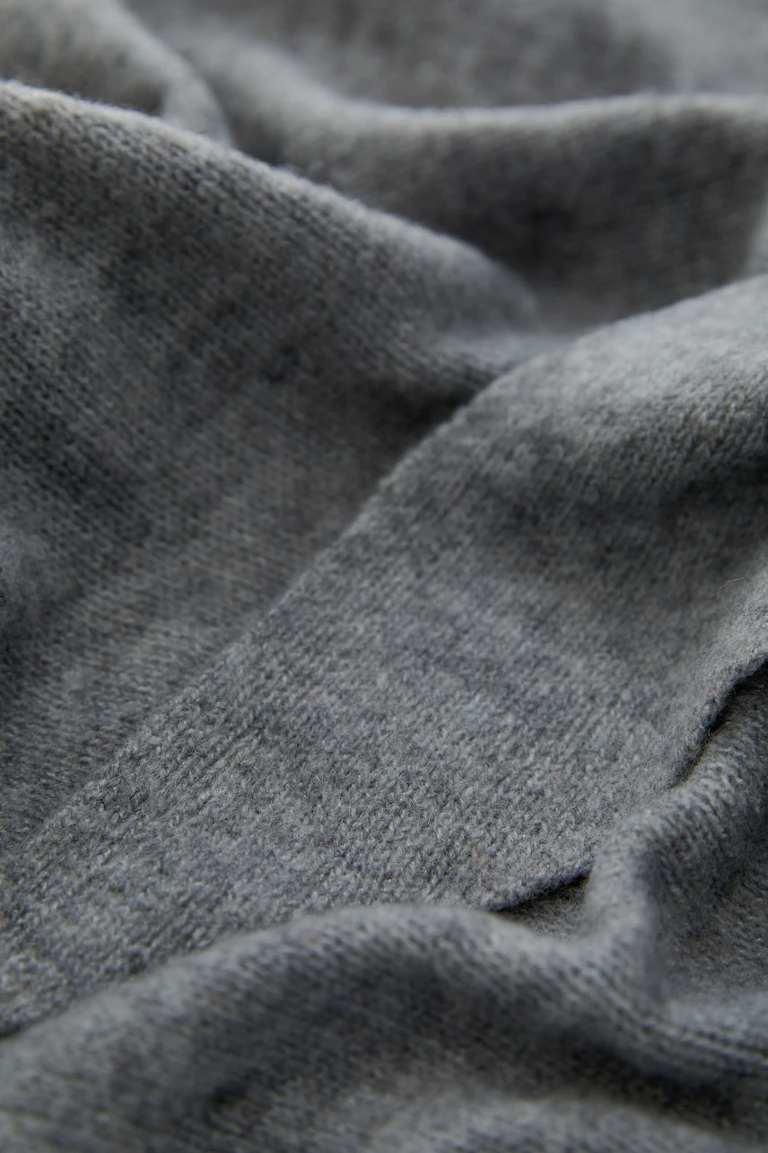 Soft grey scarf with textured fabric, perfect for layering and adding warmth to any outfit.