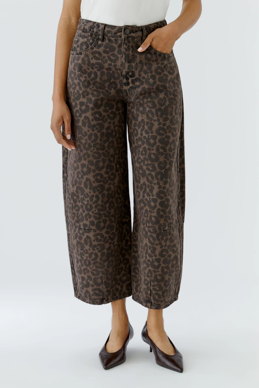 Frau in Jeans Barrel mit Leopardenmuster, weißem Top und spitzen Schuhen. Lässiger, modischer Look.