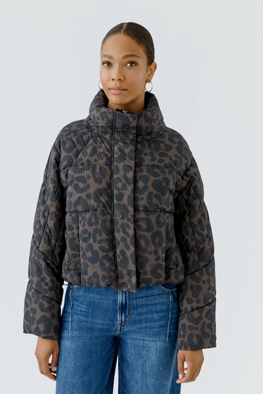 Casual outdoor jacket: Woman in leopard print puffer jacket with high collar, paired with blue jeans.