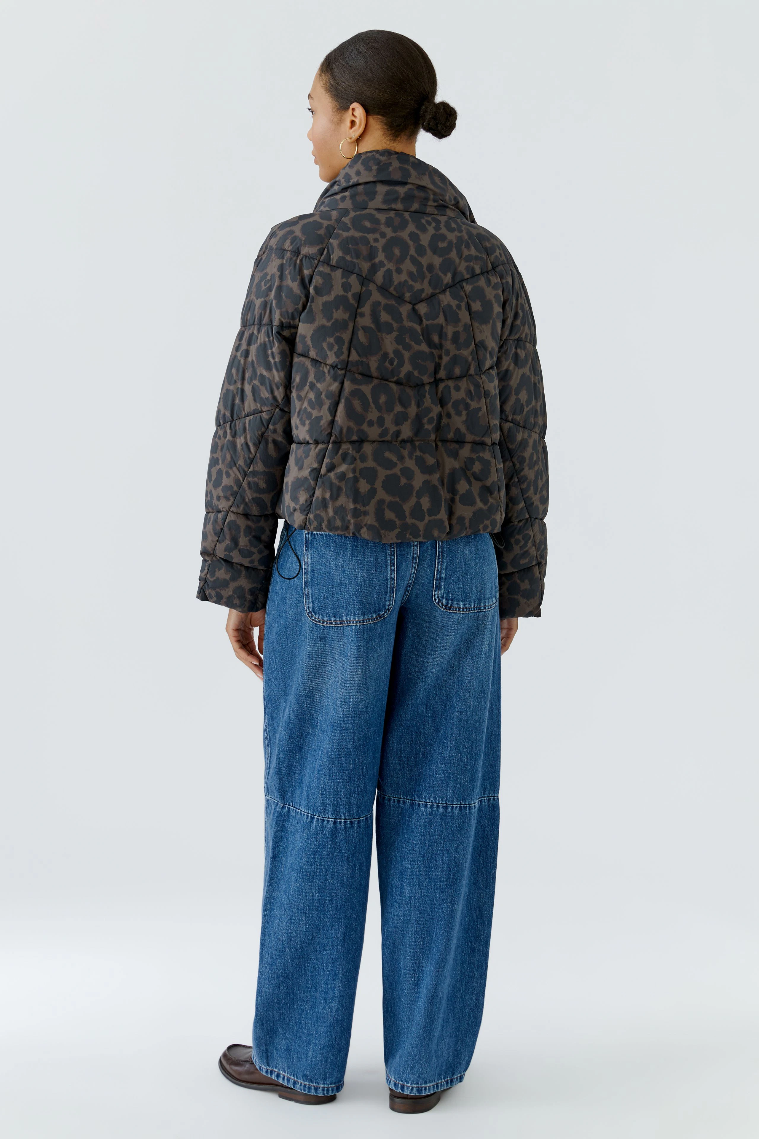 Casual outdoor jacket: Woman in leopard print puffer jacket and wide-leg jeans, viewed from the back.