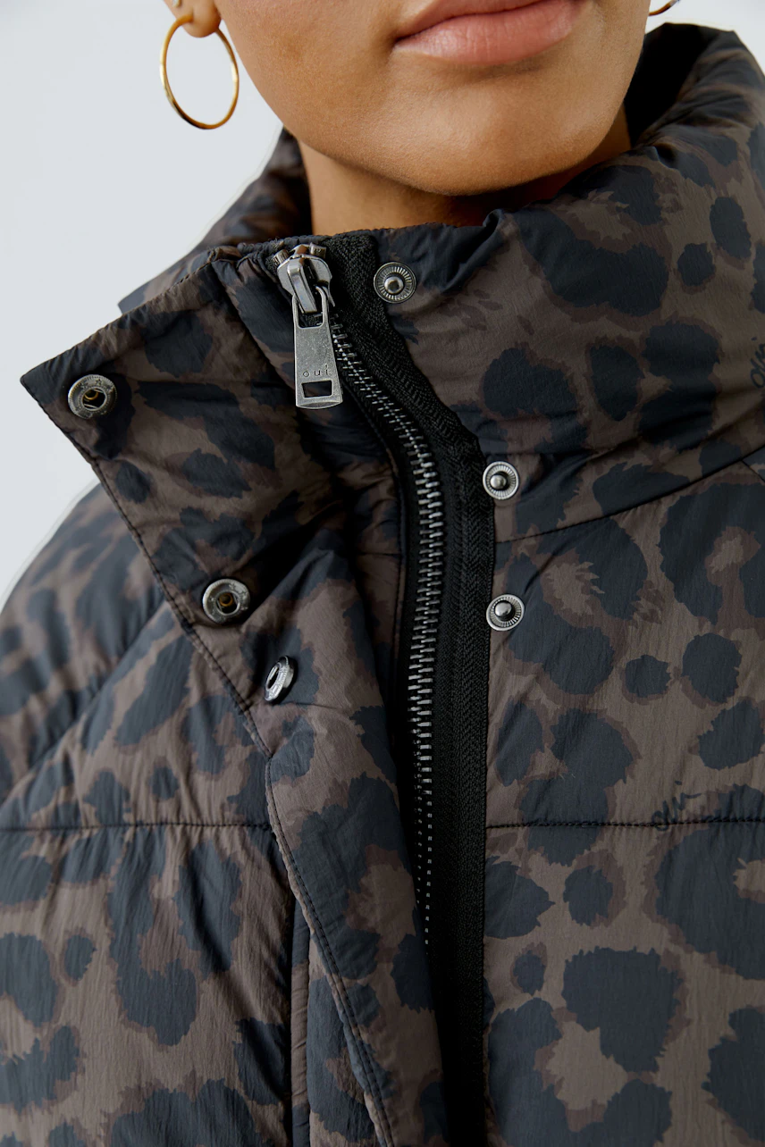 Woman in leopard print outdoor jacket with high collar and zipper detail, showcasing modern style.