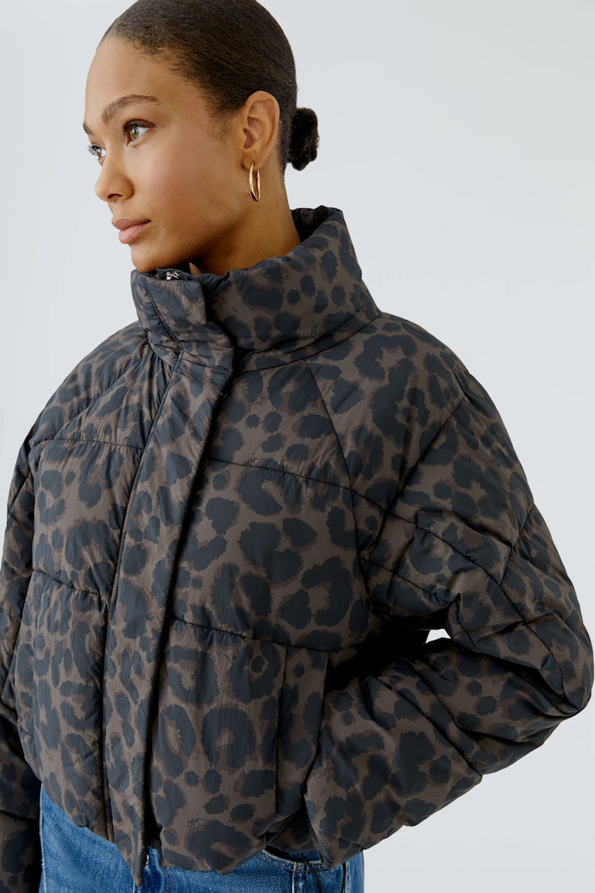 Casual outdoor jacket: Woman in leopard print puffer jacket with high collar, looking to the side.