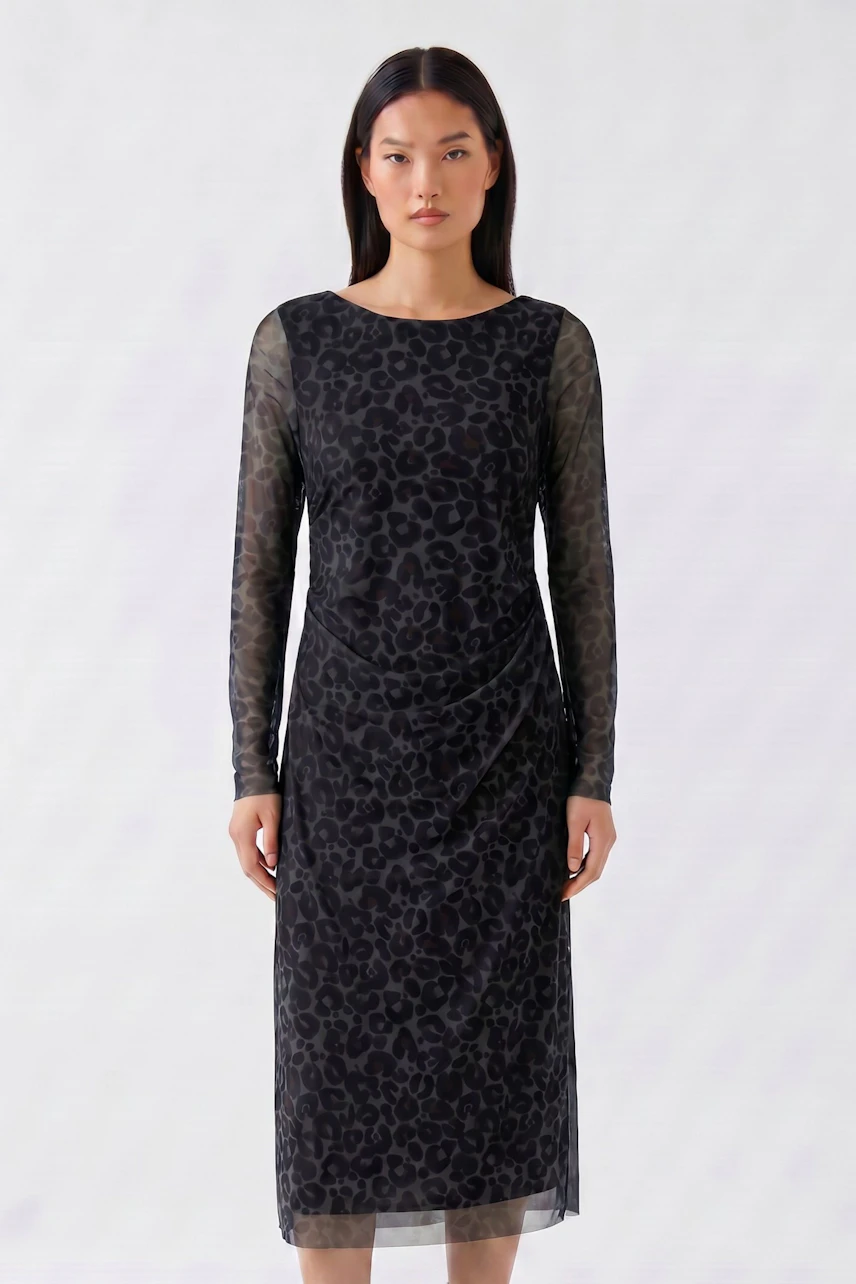 Woman in a patterned midi dress with sheer sleeves, standing confidently.