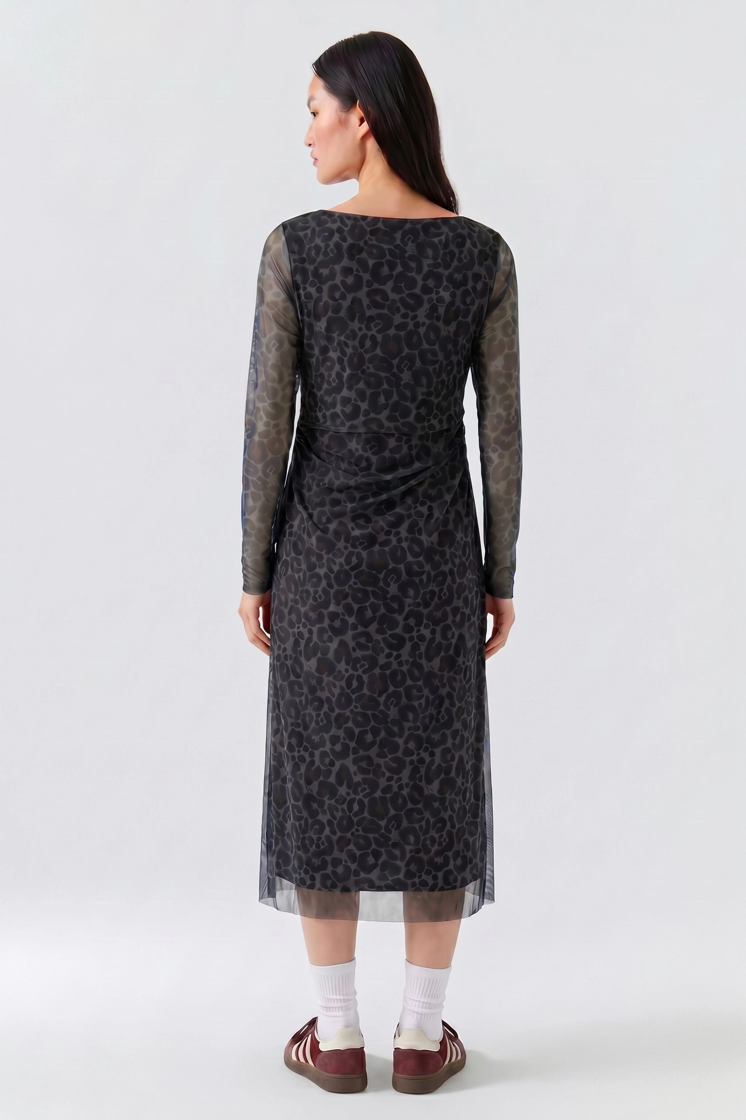 Frau im gemusterten Midikleid mit langen Ärmeln, Rückansicht. Schlichtes Design, ideal für den Alltag.