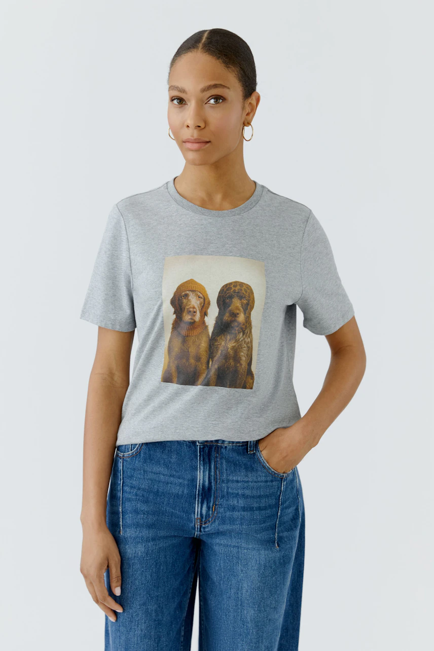 Graues Damen-T-Shirt: Frau trägt T-Shirt mit Hundeprint, kombiniert mit blauen Jeans.