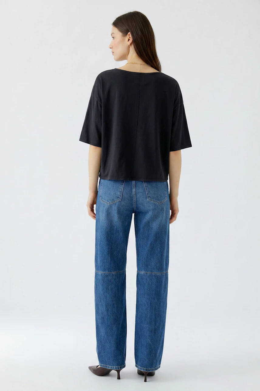 Schwarzes Damen-T-Shirt: Frau im lässigen T-Shirt und blauer Jeans von hinten, schlicht und modern.