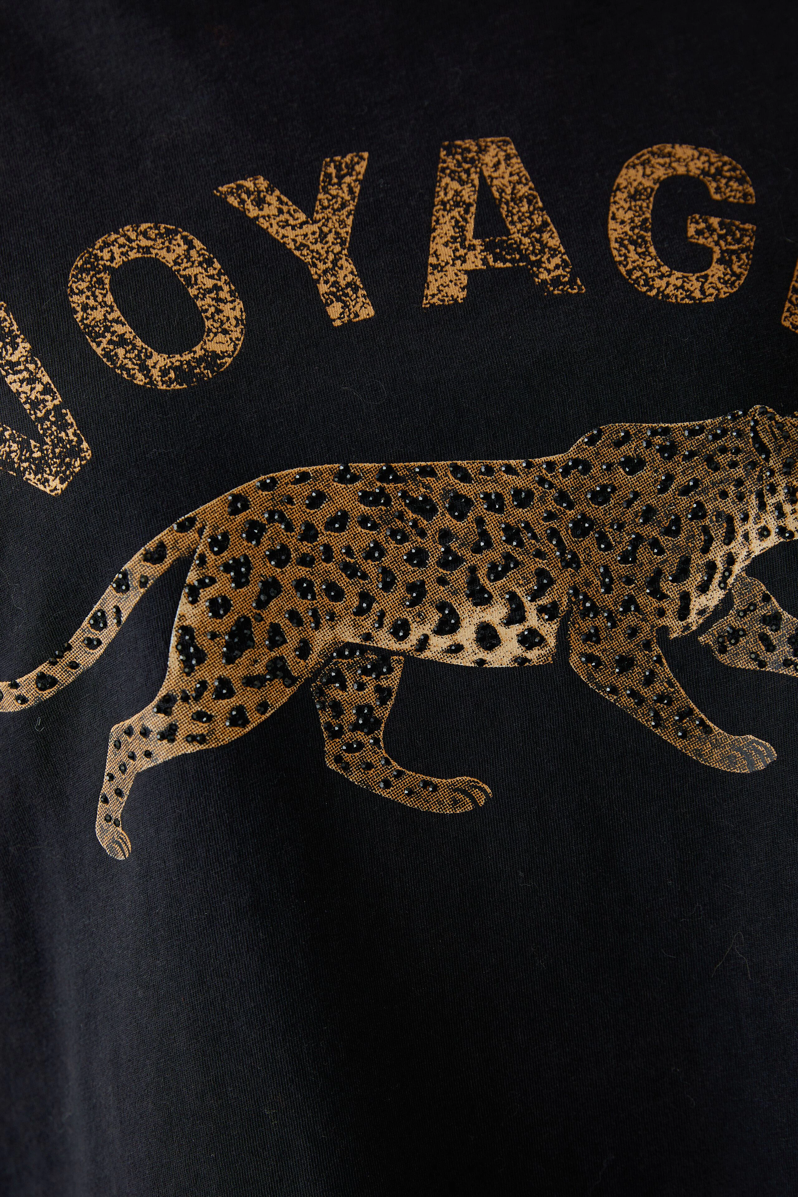 Black T-shirt with leopard print and 'Voyage' text, no model visible.