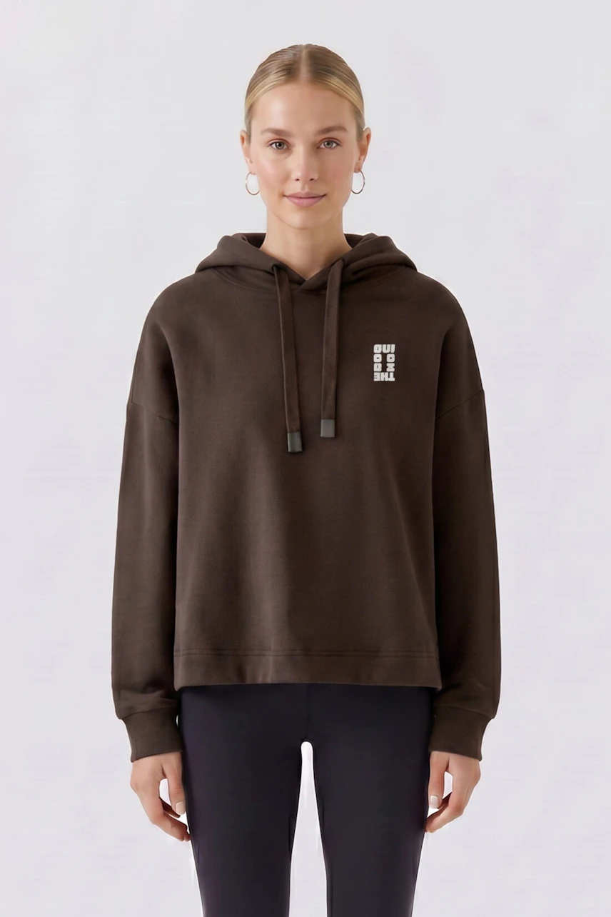 Casual women's hoodie: Woman in a brown hoodie with subtle logo, paired with black leggings, looks relaxed.