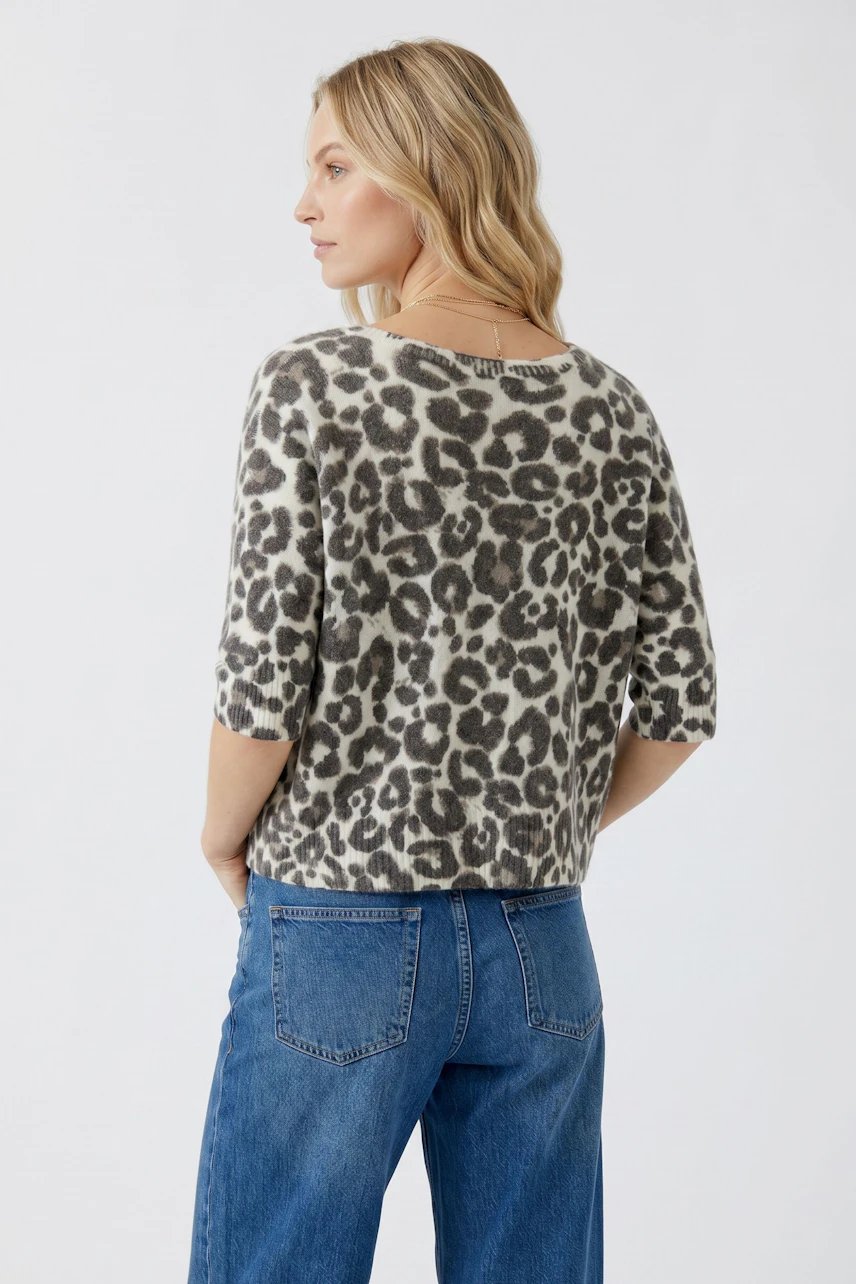 Casual cardigan: Woman in leopard print cardigan with short sleeves and blue jeans, looking to the side.