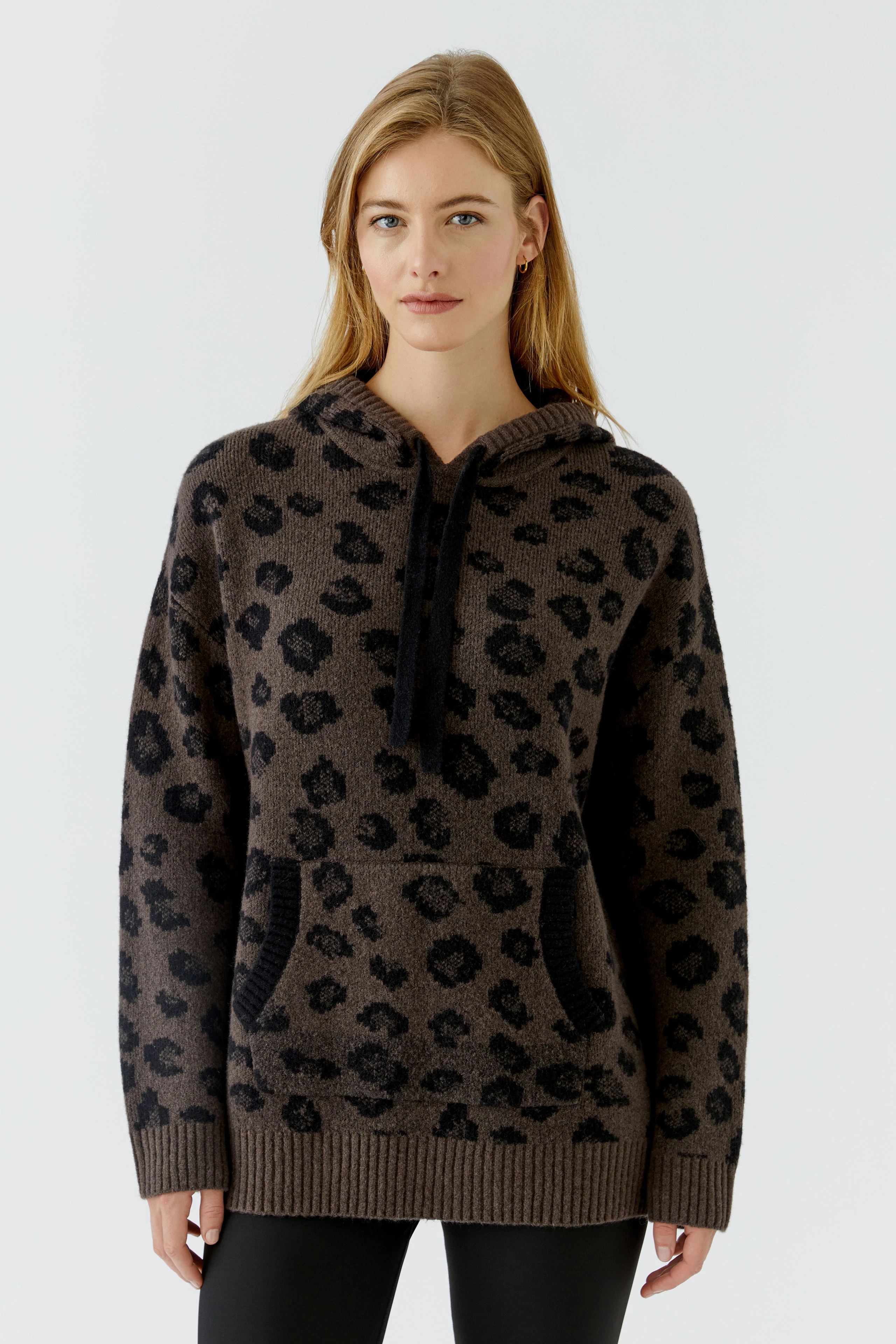 Lässiger Damen-Pullover: Frau im gemusterten Hoodie-Pullover mit Kapuze und Kängurutasche, entspanntes Design.