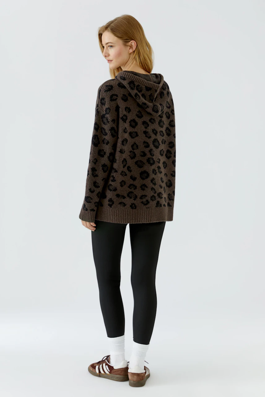 Lässiger Damen-Pullover: Frau im braunen Kapuzenpullover mit Leopardenmuster, kombiniert mit schwarzen Leggings.