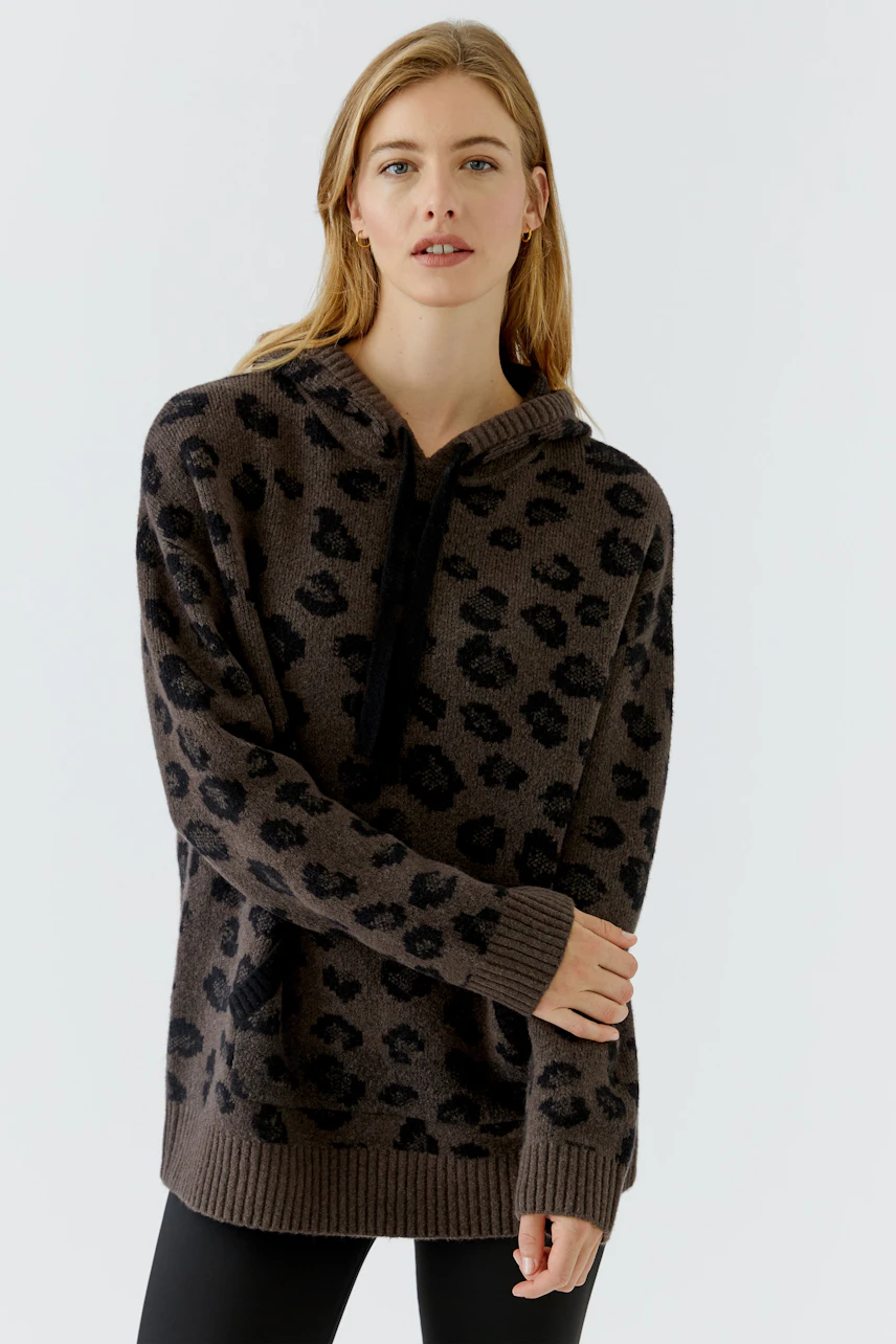 Casual women's pullover: Woman in a leopard print pullover with a relaxed fit, looking confidently.
