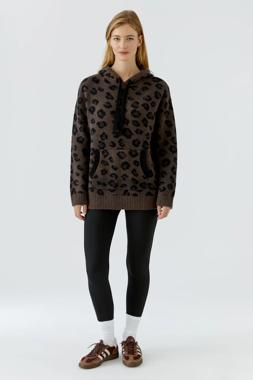 Lässiger Damen-Pullover: Frau im braunen Hoodie mit Leopardenmuster und schwarzen Leggings steht frontal.