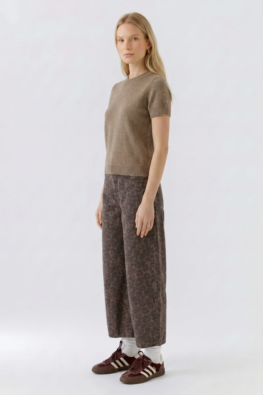 Casual women's pullover: Woman in a brown pullover with patterned pants and sneakers, standing confidently.