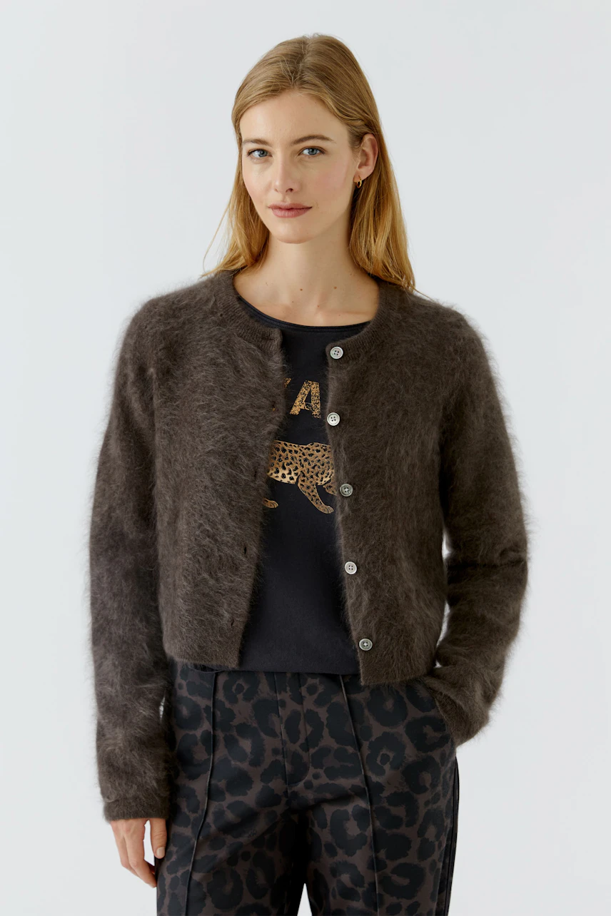 Damen-Strickjacke: Frau in brauner Strickjacke, schwarzem Shirt und blauen Jeans, lässig und modern.