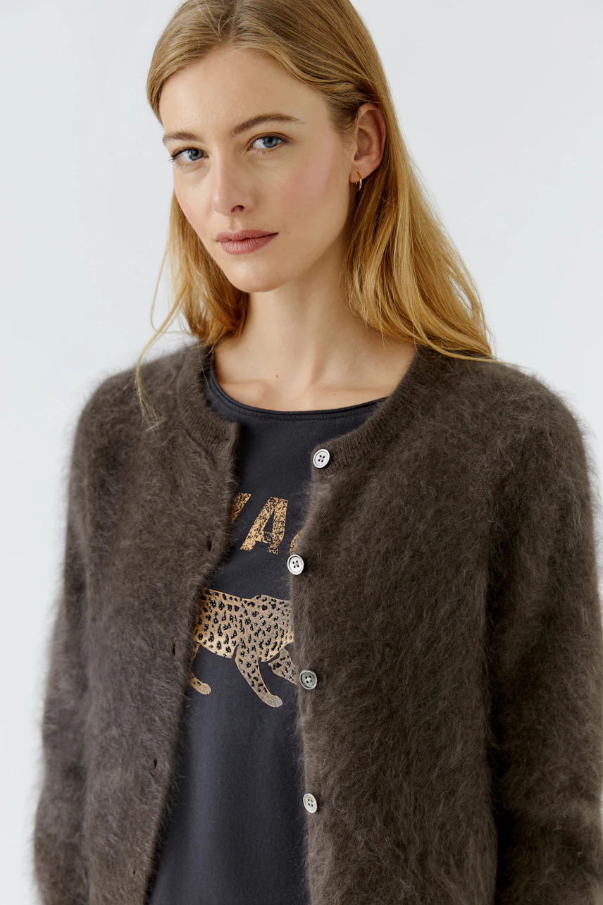 Woman in cozy cardigan: A young woman wears a soft, buttoned cardigan over a graphic tee, looking relaxed.