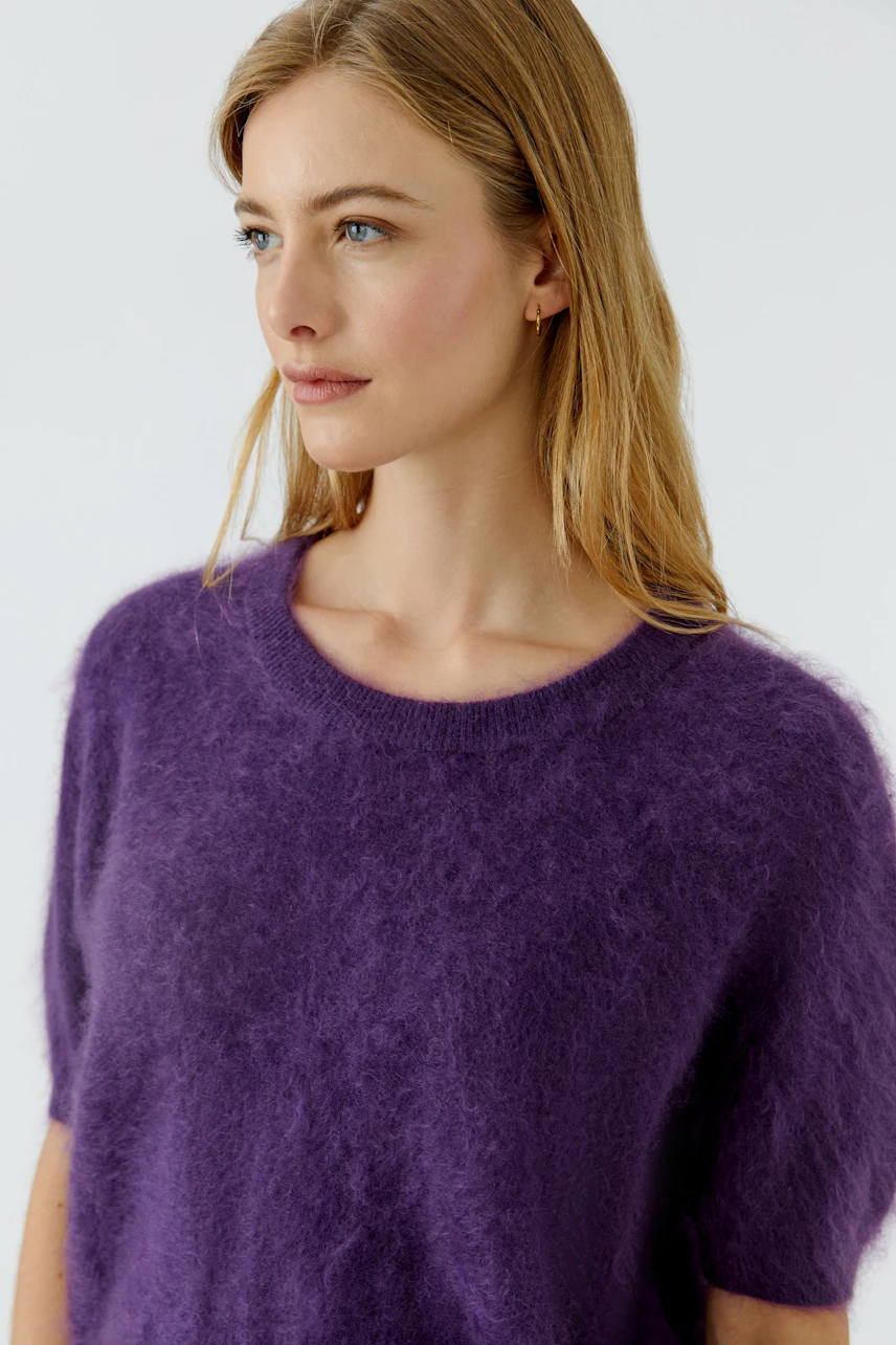 Lässiger Damen-Pullover: Frau im flauschigen lila Pullover mit kurzen Ärmeln schaut zur Seite.