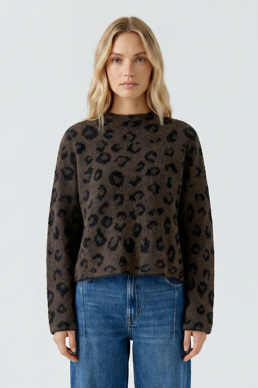 Lässiger Damen-Pullover: Frau im braunen Pullover mit Leopardenmuster und blauer Jeans schaut direkt.