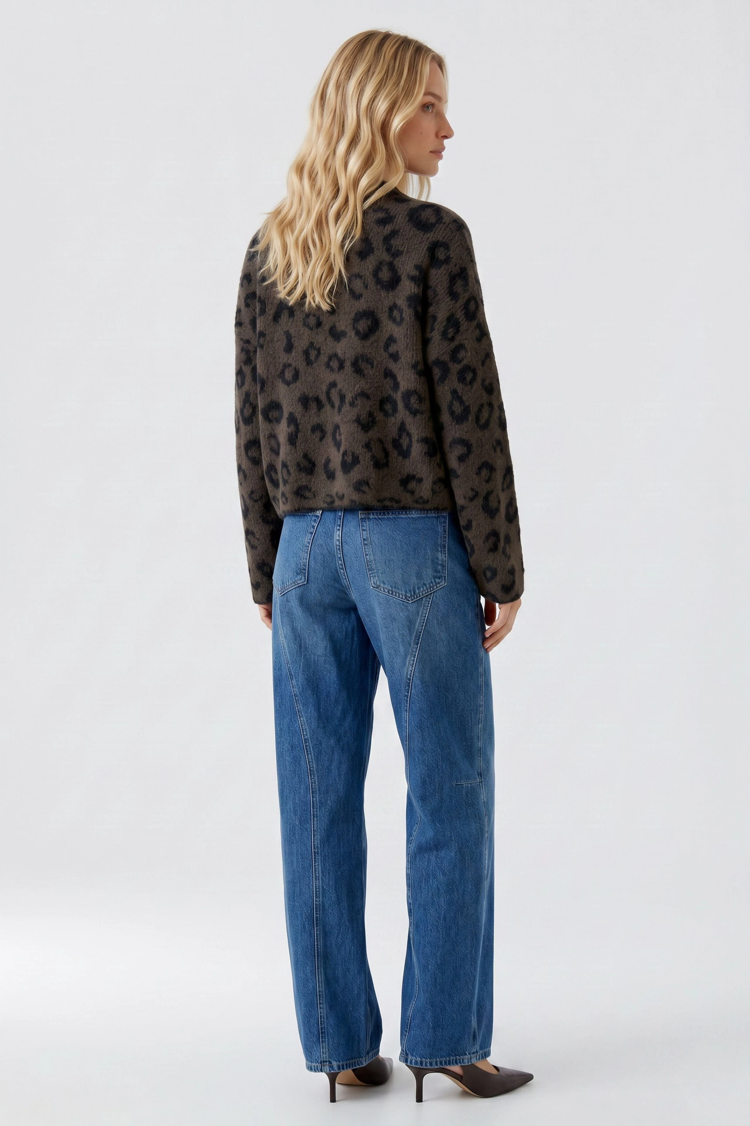 Lässiger Damen-Pullover: Frau im Leopardenmuster-Pullover und blauen Jeans von hinten zu sehen.