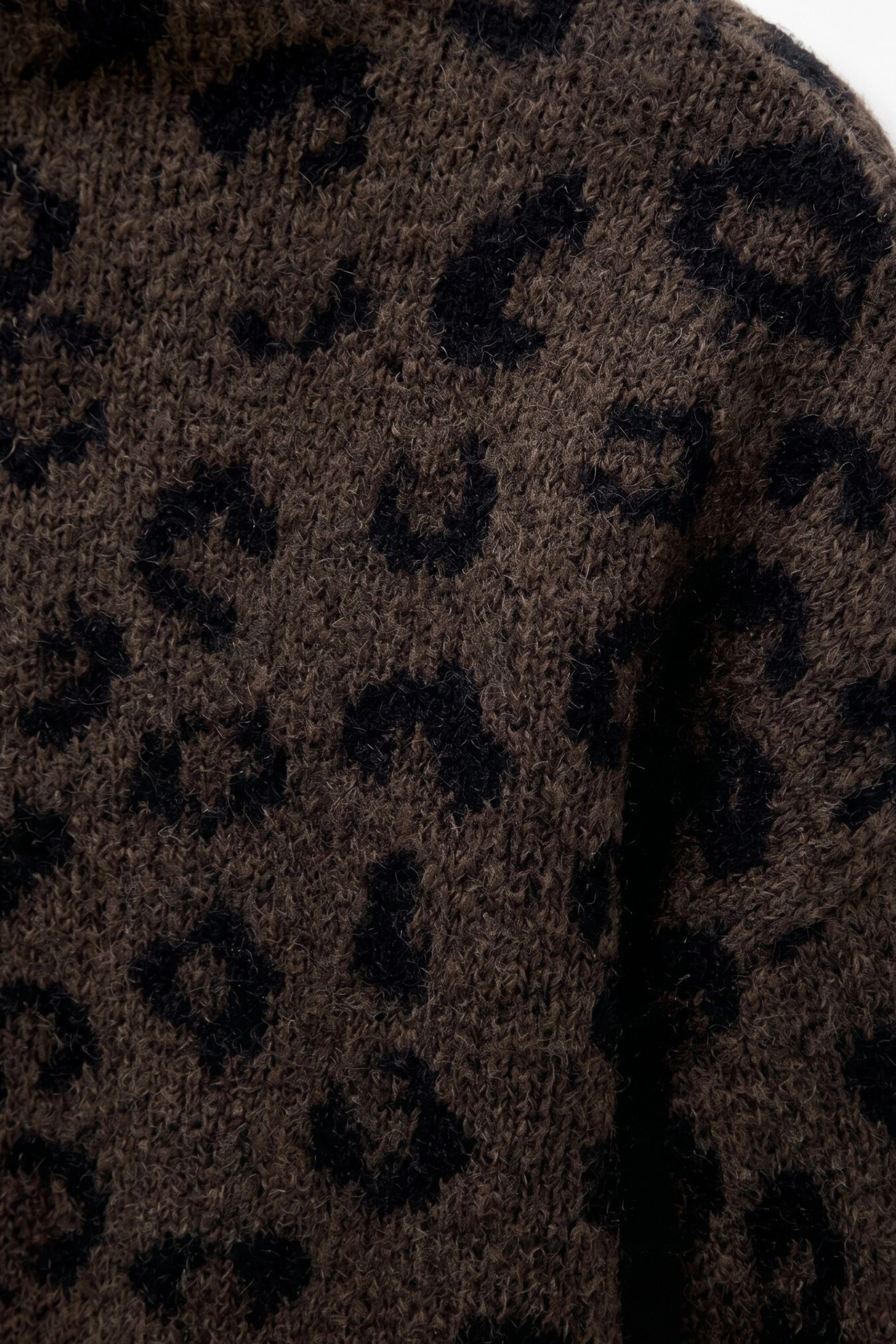 Leopardenmuster-Pullover: Nahaufnahme eines braunen Strickpullovers mit schwarzem Leopardenmuster.