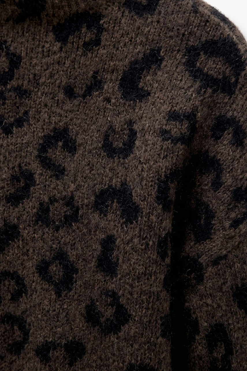 Leopardenmuster-Pullover: Nahaufnahme eines braunen Strickpullovers mit schwarzem Leopardenmuster.