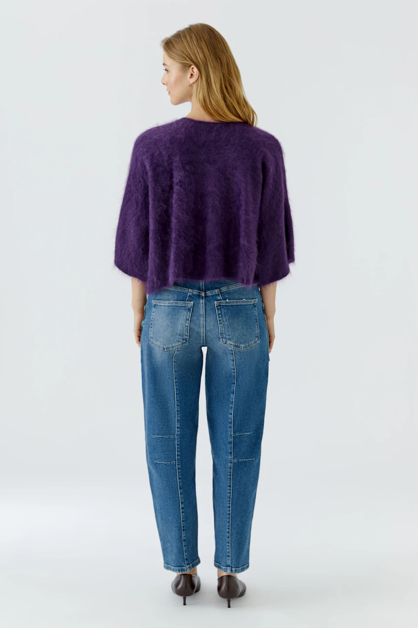 Casual pullover: Woman in a purple fuzzy pullover and blue jeans, viewed from the back.