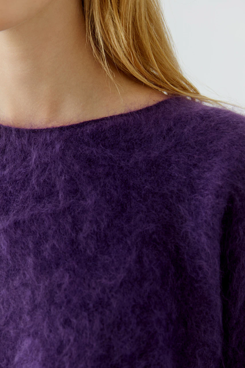 Woman in a soft purple pullover, showcasing a cozy and stylish look.