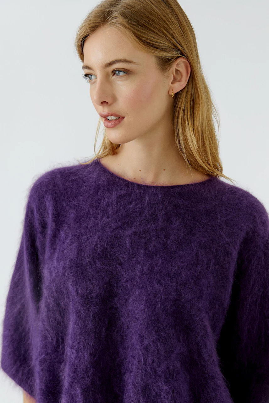 Woman in a purple fuzzy pullover, looking to the side, showcasing the soft texture and relaxed fit.