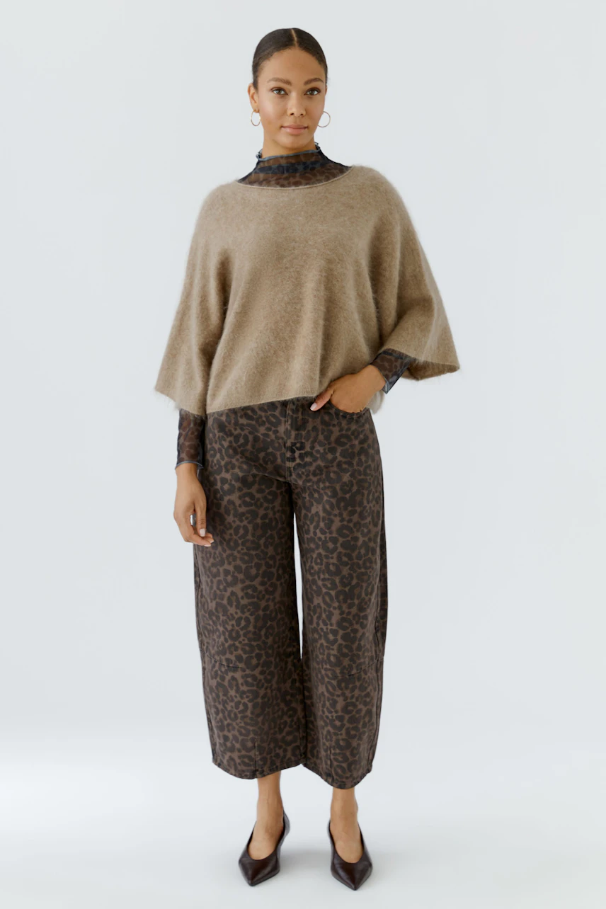 Damen-Pullover: Frau im beigen Pullover mit weitem Schnitt und gemusterten Hosen, lässig und modern.